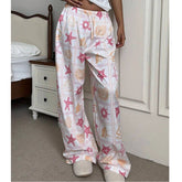 Person wearing a pair of pajama pants with starfish and shell pattern in a bedroom setting.